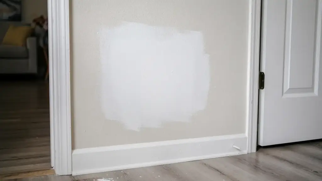 A patched drywall section beside a door frame, ready for paint